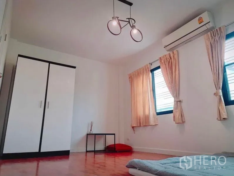 Townhouse for rent in Suan Luang, Bangkok - Bright bedroom with wood flooring, wardrobe, two windows, AC and pendant light