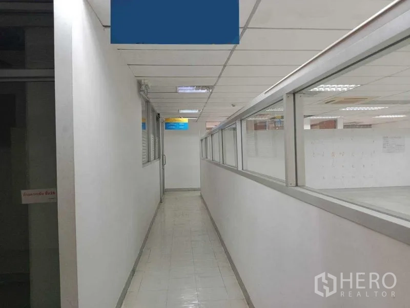 Office Space for rent in Watthana, Bangkok - Interior hallway with glass partitions and tiled floor beside the open office area.