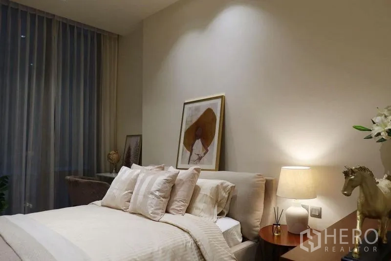 公寓 出租在Pathum Wan, Bangkok - 静谧卧室，软包床、浅色床品与床头灯，配高挑窗帘