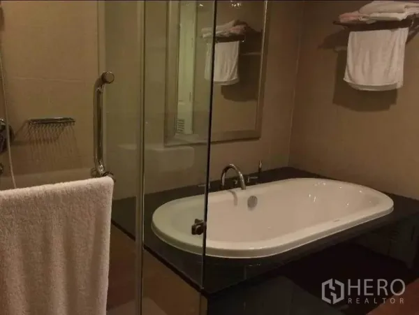 คอนโด ขายในPathum Wan, Bangkok - ห้องน้ำพร้อมอ่างอาบน้ำแบบฝัง พาร์ทิเชนกระจก และราวแขวนผ้าเช็ดตัว