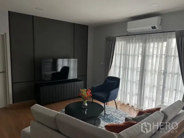 Detached House for rent or sale in Bang Phli, Samut Prakan - Bright TV lounge with floor‑to‑ceiling curtains, air conditioner and a modern media cabinet.