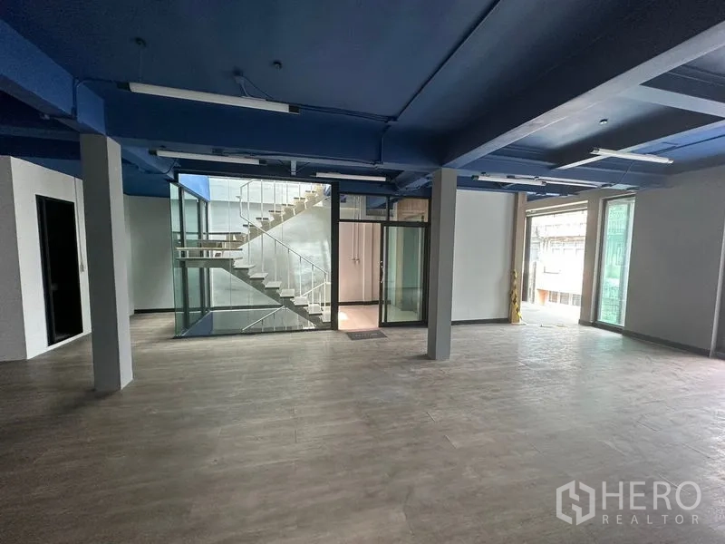 สำนักงาน ให้เช่าในWatthana, Bangkok - พื้นที่สำนักงานเปิดโล่ง เพดานสีน้ำเงิน พื้นลายไม้ และแกนบันไดกระจก