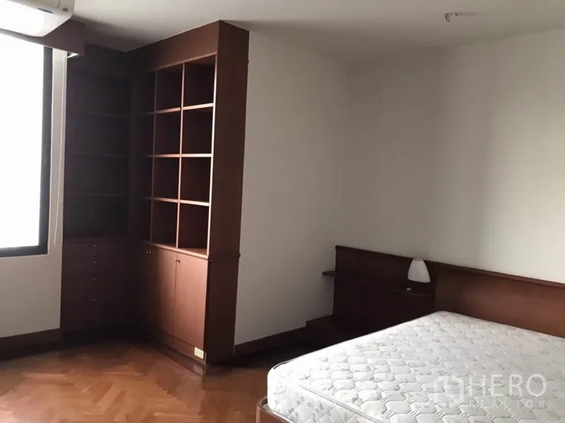 Condominium for rent or sale in Watthana, Bangkok - Bedroom corner with window and floor-to-ceiling shelving units.