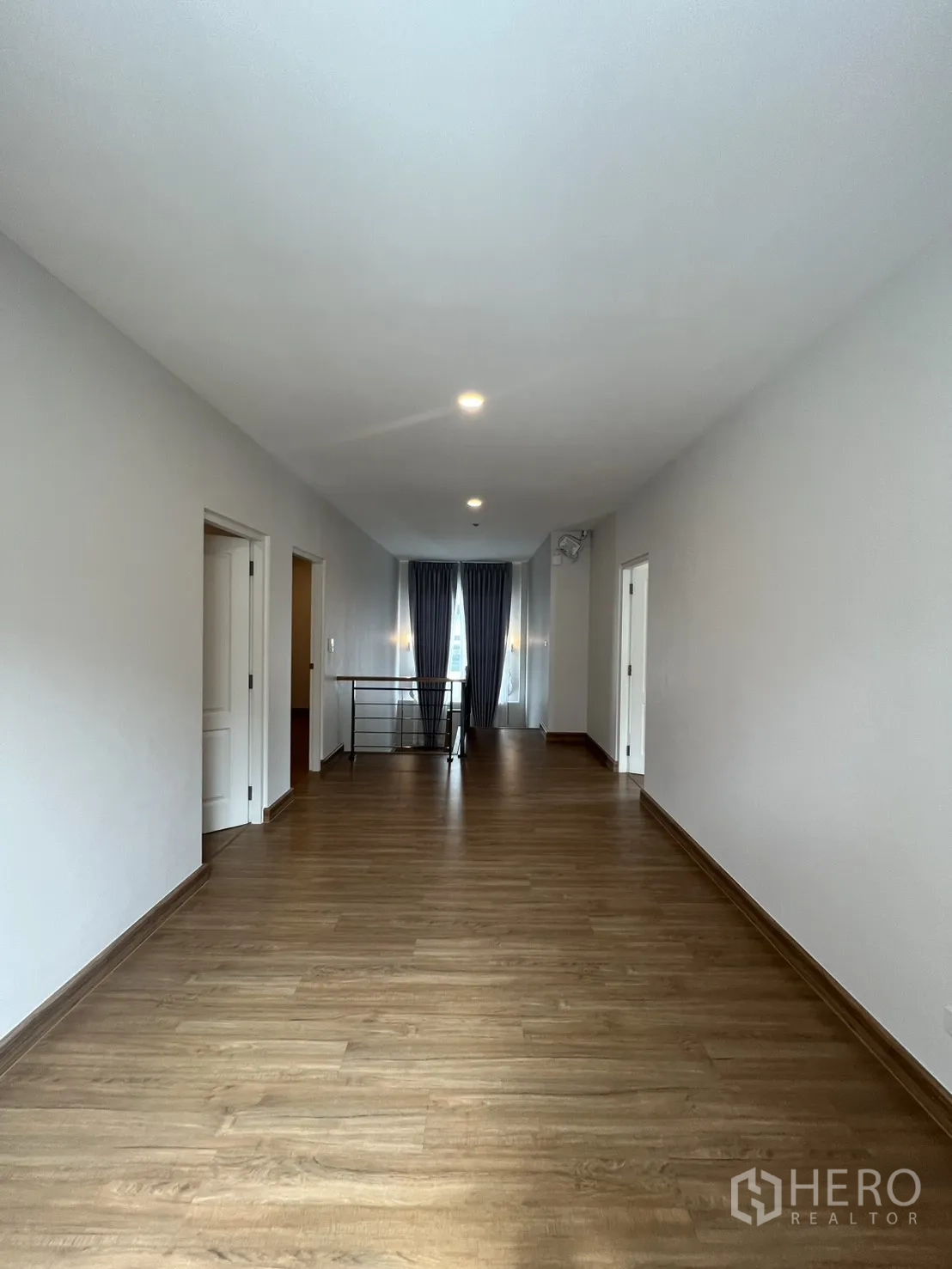 Detached House for rent in Lat Krabang, Bangkok - Long upper hallway with wood floors and lighting leading to the stair railing.
