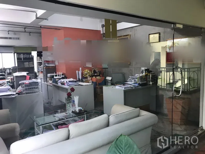 Office Space for rent in Watthana, Bangkok - Open-plan office behind glass partition with multiple desks, sofa seating and organized workstations.