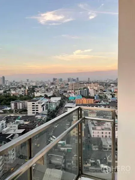 Condominium for rent or sale in Watthana, Bangkok - High-floor balcony with glass railing overlooking Bangkok skyline at sunset.