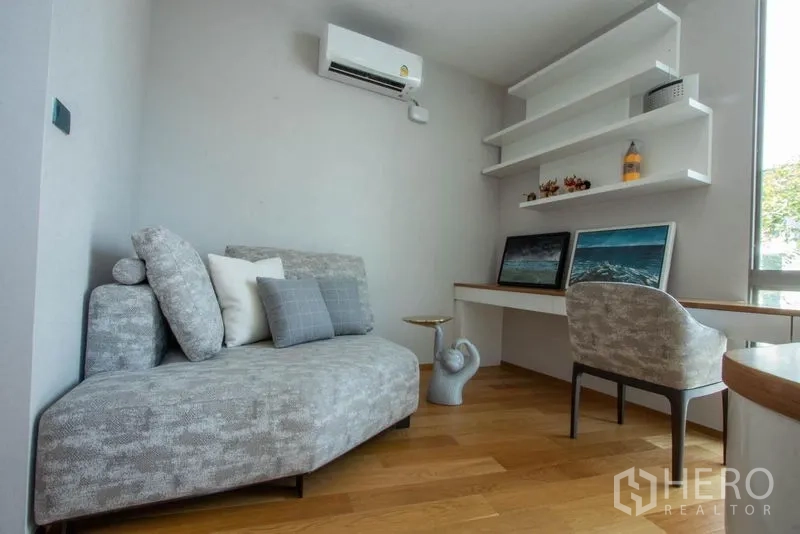 Detached House for sale in Saphan Sung, Bangkok - Compact home office with sofa, wall shelves, desk and window.