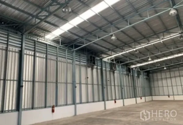 Warehouse for rent in Suan Luang, Bangkok - Side view of the warehouse interior showing ventilation louvers, hanging bay lights, and fire extinguishers.