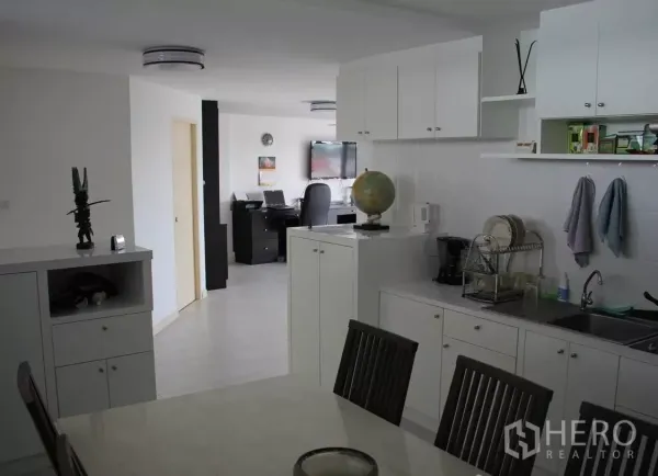 Condominium for sale in Wang Thonglang, Bangkok - White open kitchen with ample cabinetry and a view toward the living and work desk.