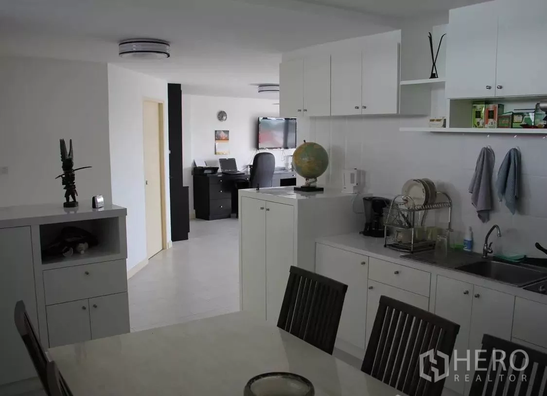 Condominium for sale in Wang Thonglang, Bangkok - White open kitchen with ample cabinetry and a view toward the living and work desk.