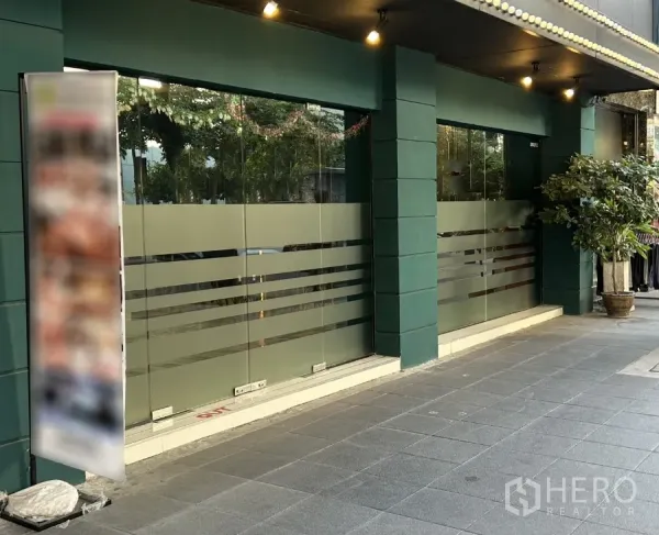 零售空间 出租在Khlong Toei, Bangkok - 街角临街店面，整面磨砂玻璃橱窗、绿色立柱与有顶人行道，素坤逸商圈。