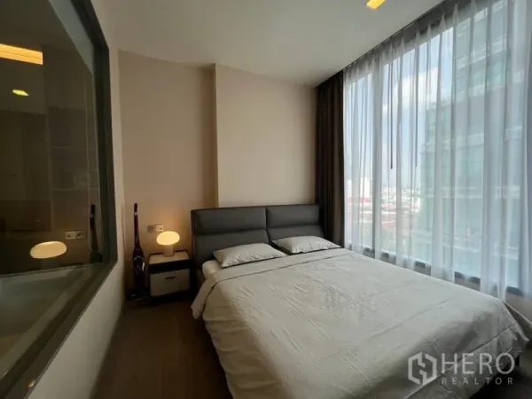 Condominium for rent in Watthana, Bangkok - Bright bedroom with floor-to-ceiling windows, city view, and a queen bed in a Watthana condominium.