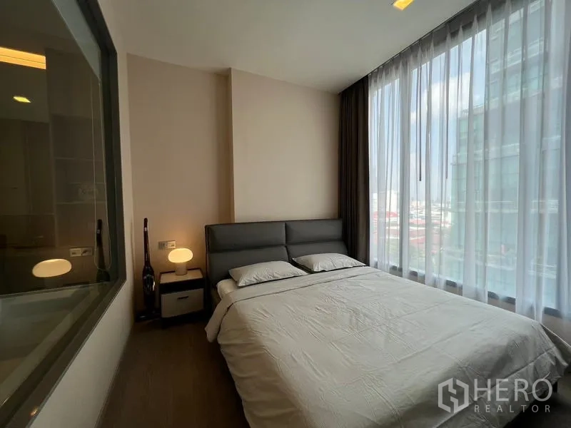 Condominium for rent in Watthana, Bangkok - Bright bedroom with floor-to-ceiling windows, city view, and a queen bed in a Watthana condominium.