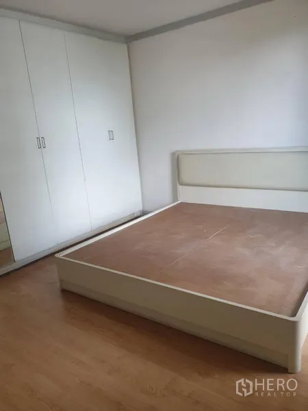 Condominium for rent in Watthana, Bangkok - Bedroom with white wardrobe and platform bed on wood flooring.