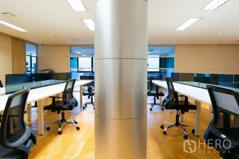 办公空间 出租在Khlong Toei, Bangkok - 开放式办公区，长条工位、网面椅、木地板，中央金属立柱。
