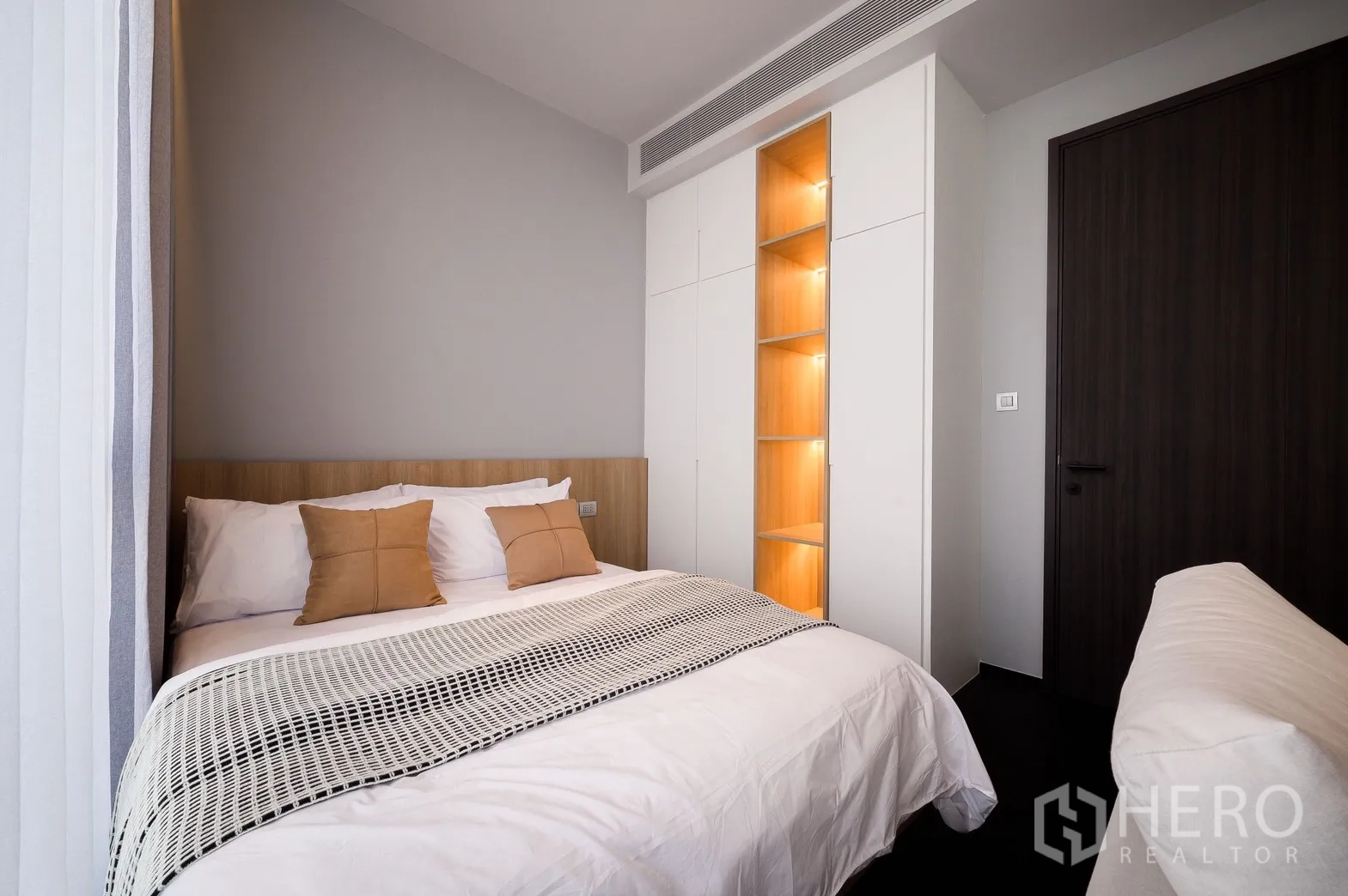 Condominium for rent or sale in Watthana, Bangkok - Bedroom with double bed, accent pillows and illuminated built-in wardrobe shelving.