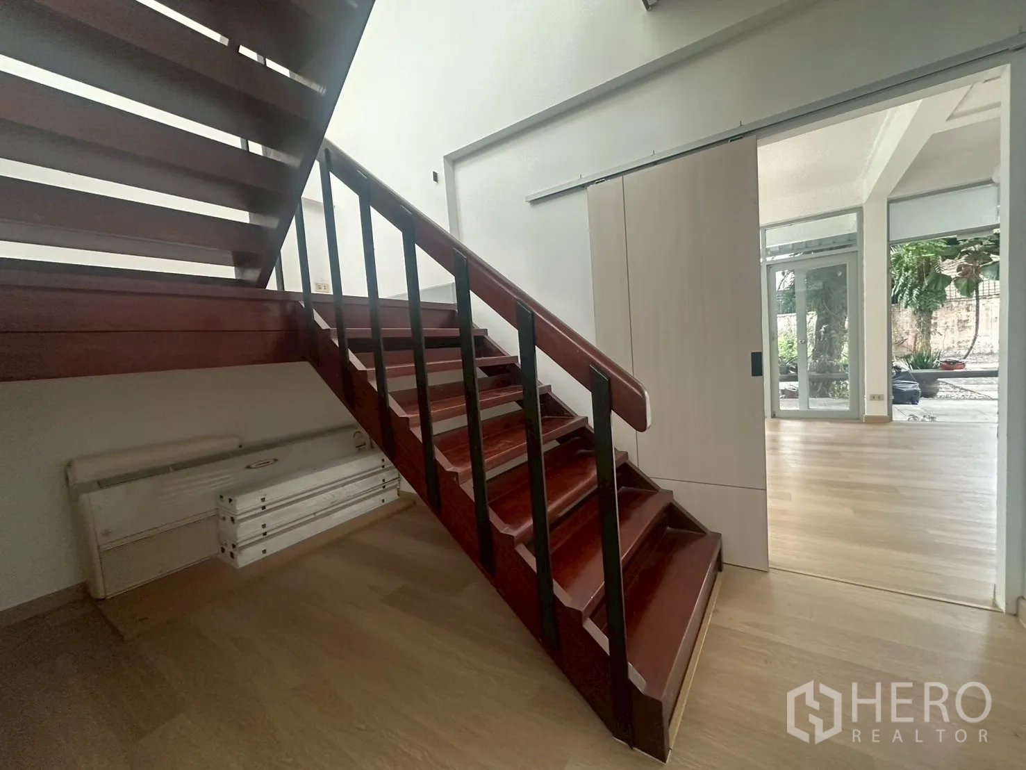 บ้าน ให้เช่าในWatthana, Bangkok - บันไดไม้โทนเข้มอยู่ข้างประตูบานเลื่อนทางเข้า.