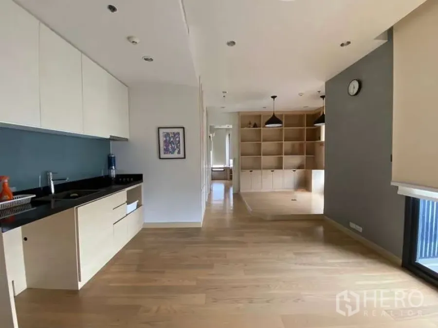 公寓 出租或出售在Chatuchak, Bangkok - 长廊式厨房，浅色橱柜通向客厅及定制置物架。