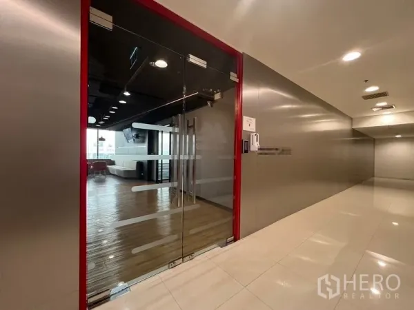 办公空间 出租在Huai Khwang, Bangkok - 红色边框的玻璃门入口，通往木地板接待休息区。