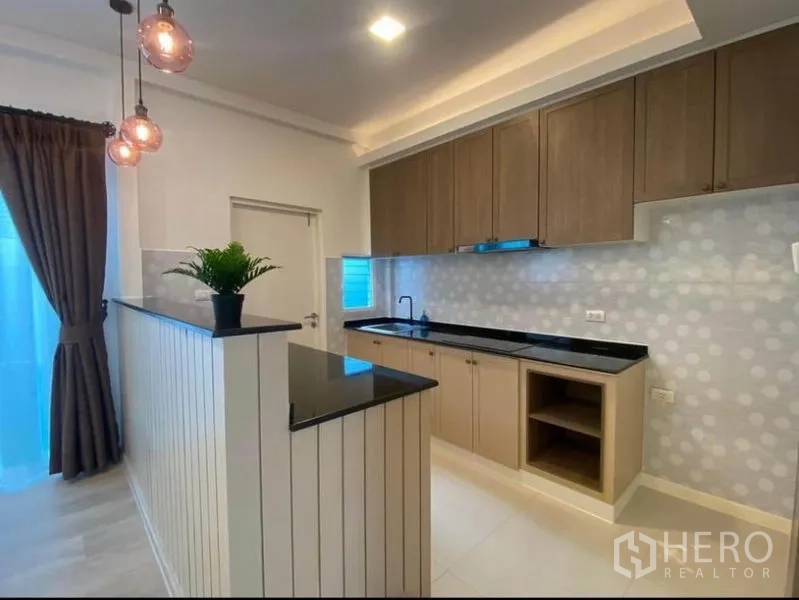 联排别墅 出租在Prawet, Bangkok - 开放式厨房，吧台、木柜与圆点瓷砖背景墙。