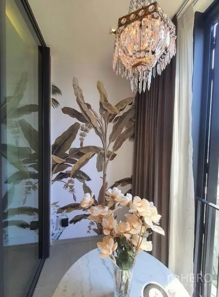 คอนโด ให้เช่าในKhlong Toei, Bangkok - โคลสอัพมุมนั่งเล่นรับแสง โคมคริสตัล ผนังลายดอกไม้ โต๊ะกลม และแจกันใกล้หน้าต่างสูง