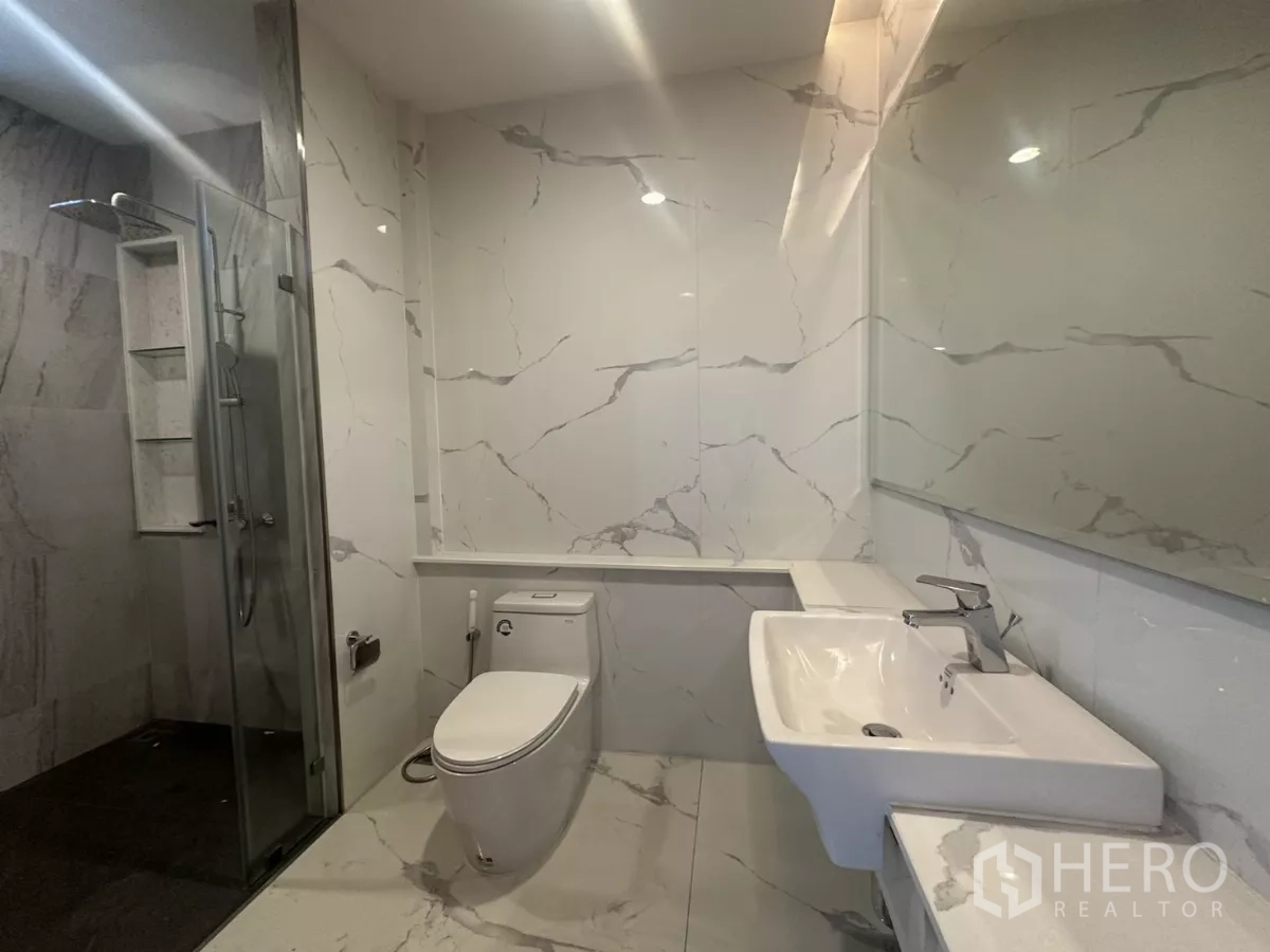 Townhouse for rent in Watthana, Bangkok - Bright bathroom with rain shower, glass door and marble-look finishes.