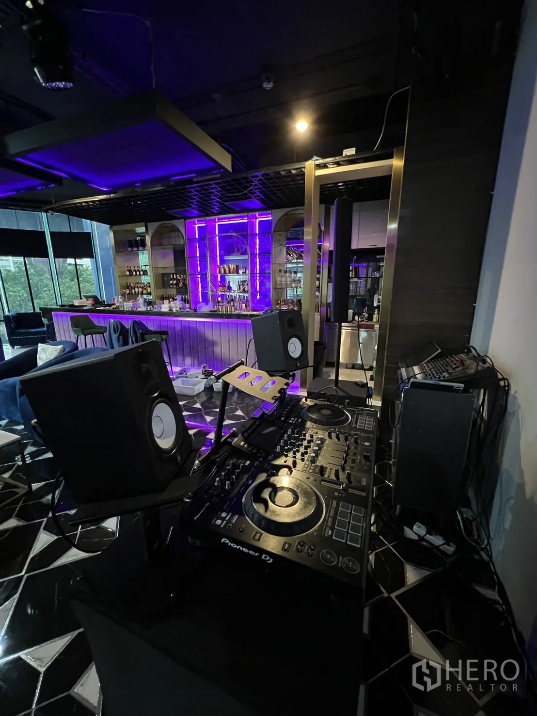 พื้นที่ขายปลีก ให้เช่า - บูธดีเจและอุปกรณ์เสียงตั้งอยู่หน้าบาร์ที่มีไฟสีม่วง