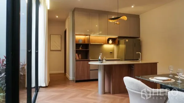 独立式住宅 出租或出售在Bang Kapi, Bangkok - 现代西式厨房，带岛台，木质柜体与暖色灯带。