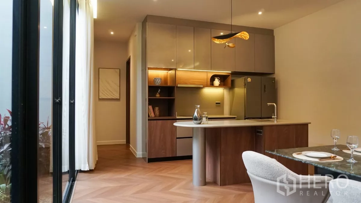 独立式住宅 出租或出售在Bang Kapi, Bangkok - 现代西式厨房，带岛台，木质柜体与暖色灯带。