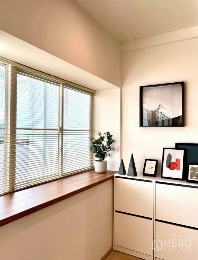 联排别墅 出租在Prawet, Bangkok - 转角窗带百叶与木窗台，极简收纳柜摆放装饰画。