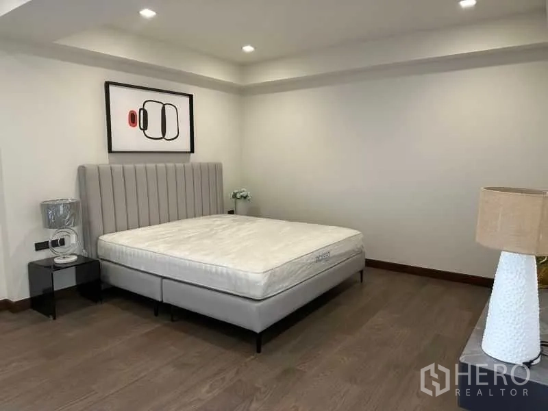 Detached House for rent in Suan Luang, Bangkok - Guest bedroom with gray upholstered bed and soft lighting.