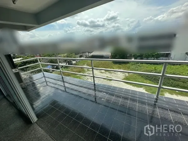 Office Space for rent - Covered tiled balcony with metal railing overlooking greenery and low-rise surroundings.