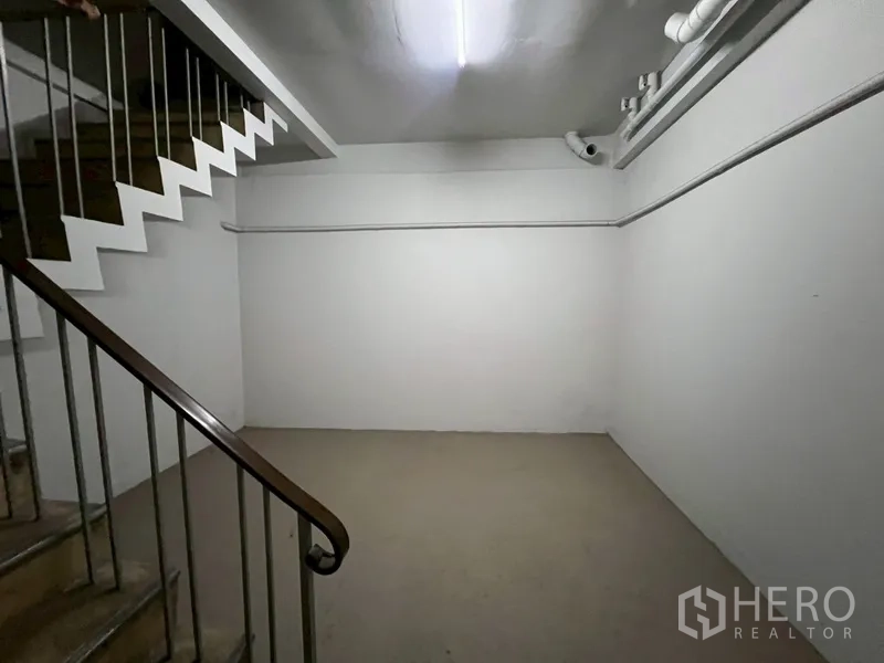 店屋 出租在Phra Khanong, Bangkok - 室内楼梯，金属扶手与白色墙面连接各层。