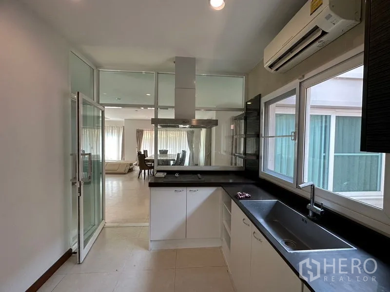 Detached House for rent or sale in Pak Kret, Nonthaburi - Kitchen view to living area through glass partition and range hood.