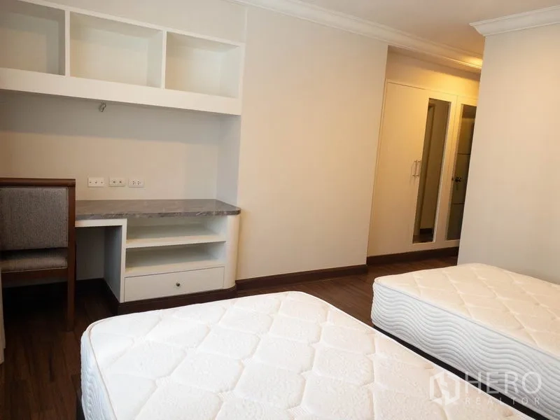 公寓 出租在Watthana, Bangkok - 卧室配双床、内置书桌与搁架，通向衣柜和浴室。