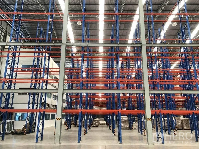 Warehouse for rent in Bang Pakong, Chachoengsao - Rows of blue and orange selective pallet racks inside a well-lit, expansive warehouse.