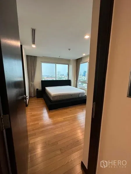 Condominium for rent in Yan Nawa, Bangkok - Bedroom with large windows, wood flooring, and city skyline views.