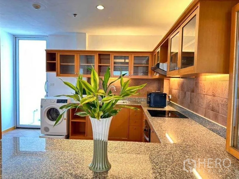 Apartment for rent - U-shaped kitchen with granite countertops, glass-front cabinets and a washing machine.