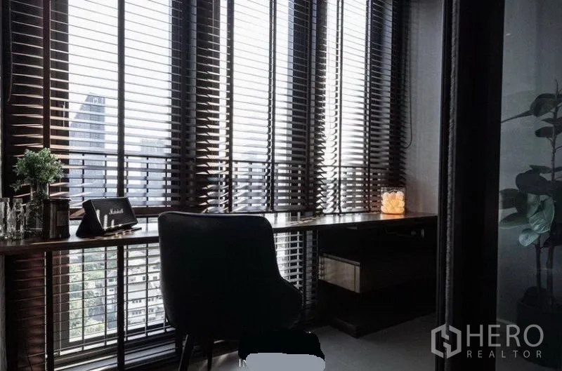 公寓 出租在Khlong Toei, Bangkok - 角落书房，长书桌贴近落地窗，百叶帘外是城市景观。