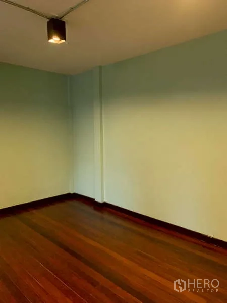 独立式住宅 出租或出售在Phra Khanong, Bangkok - 卧室一角，浅绿墙面与光滑木地板。