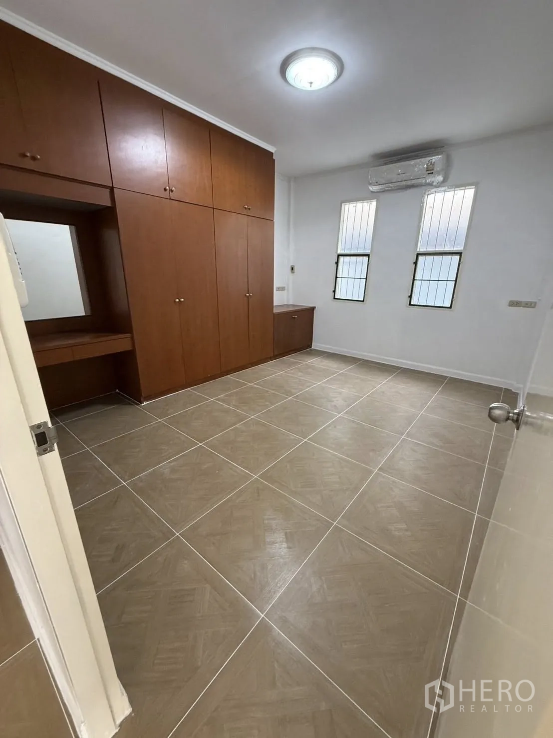 บ้านเดี่ยว for rent in Khlong Toei, Bangkok - ห้องนอนพร้อมตู้เสื้อผ้าบิลท์อินสีไม้ พื้นกระเบื้อง แอร์ และหน้าต่างสูง