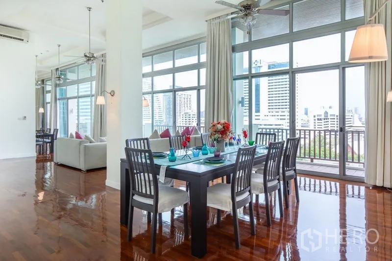 Condominium for rent in Bang Rak, Bangkok - Corner dining space beside floor-to-ceiling windows and balcony overlooking the city skyline.