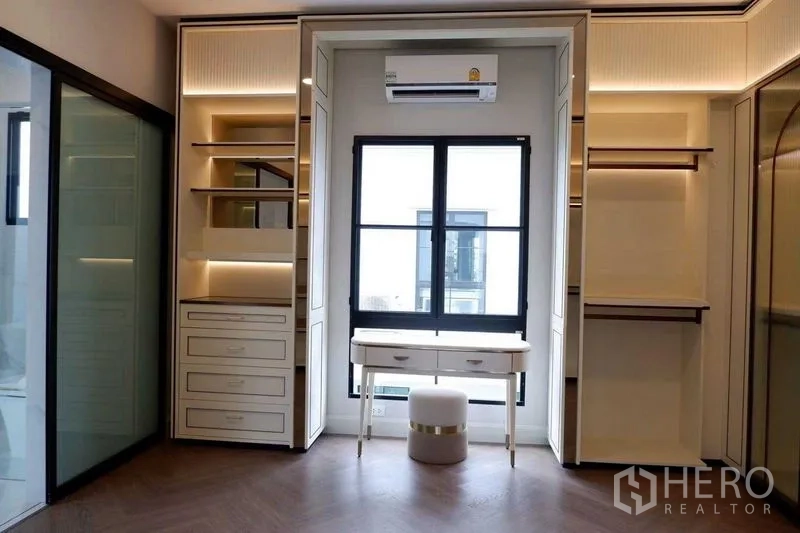 Detached House for sale in Saphan Sung, Bangkok - Walk-in closet with built-in shelving, vanity desk and warm LED accents.