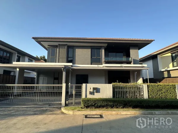 独立式住宅 出租或出售在Lam Luk Ka, Pathum Thani - 现代两层独栋别墅，带电动门车道、阳台与绿篱。