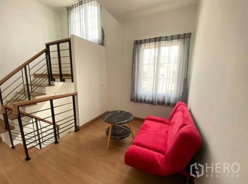 Detached House for rent or sale - Upper landing lounge with red sofa, black metal stair rail and natural light from two windows.