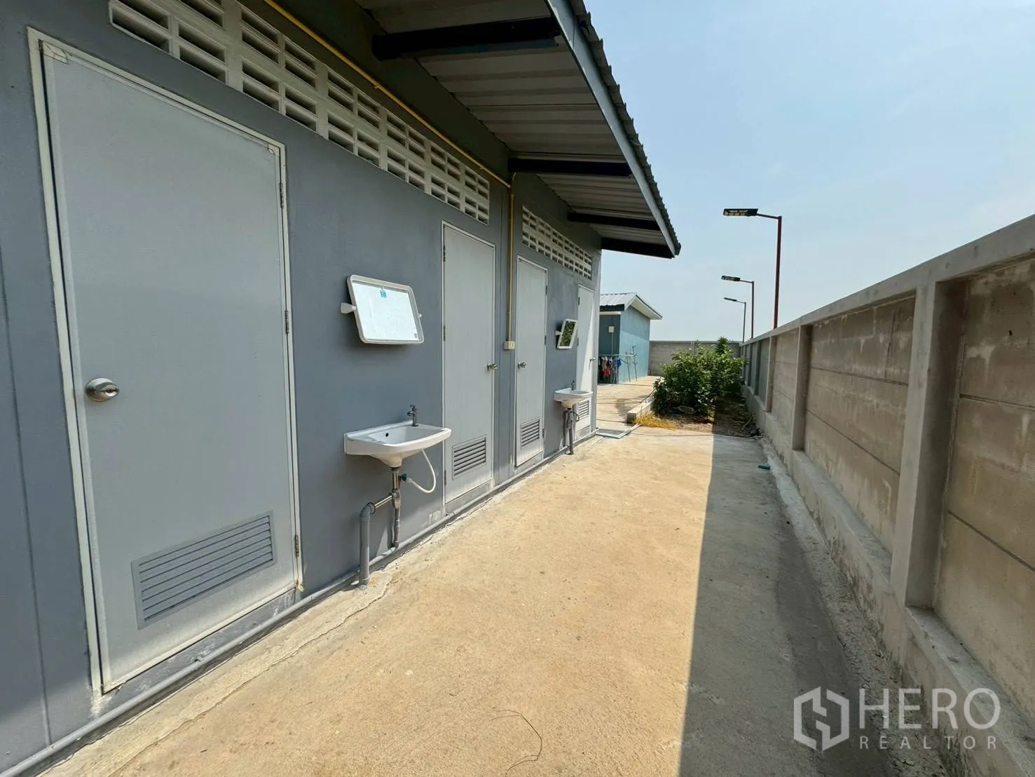 Warehouse for rent in Phutthamonthon, Nakhon Pathom - External worker restroom block with sinks along the side of the compound wall.
