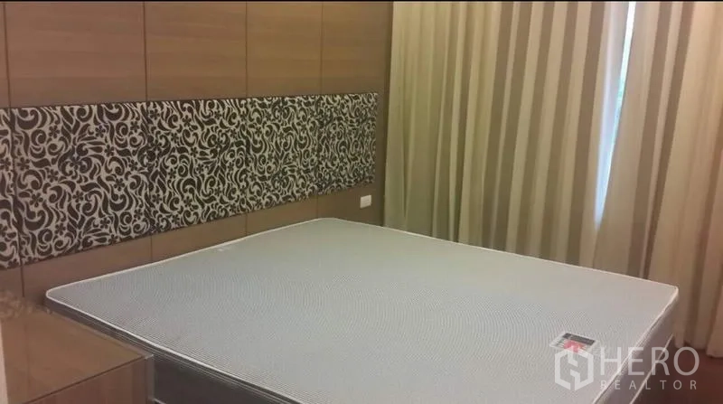 公寓 出租或出售在Ratchathewi, Bangkok - 卧室配大床与木质墙面，花纹床头板和全遮光窗帘。