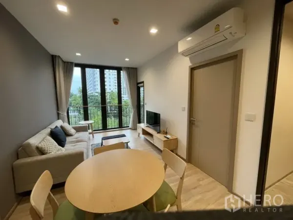 公寓 出租在Watthana, Bangkok - 开放式客餐厅，沙发、电视柜、阳台门与空调。