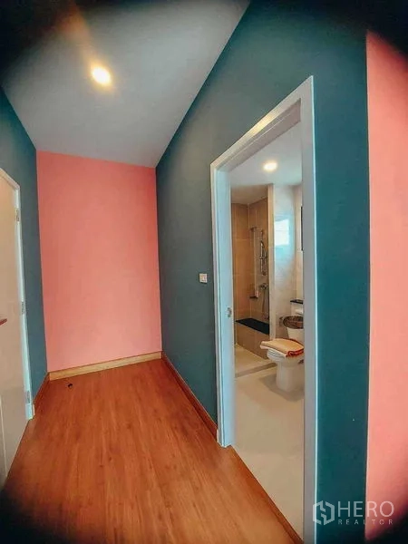 Detached House for rent in Bang Bo, Samut Prakan - Corridor with colorful walls leading to an ensuite bathroom with glass shower.