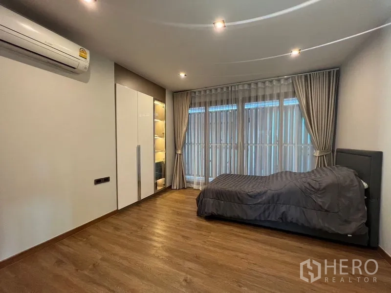 独立式住宅 出售在Chatuchak, Bangkok - 卧室配单人床、空调与落地窗纱帘，采光良好。